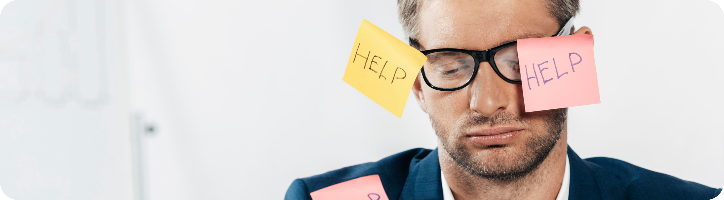 Фотография уставшего мужчины, к его очкам приклеены офисные стикеры с надписью «Help»